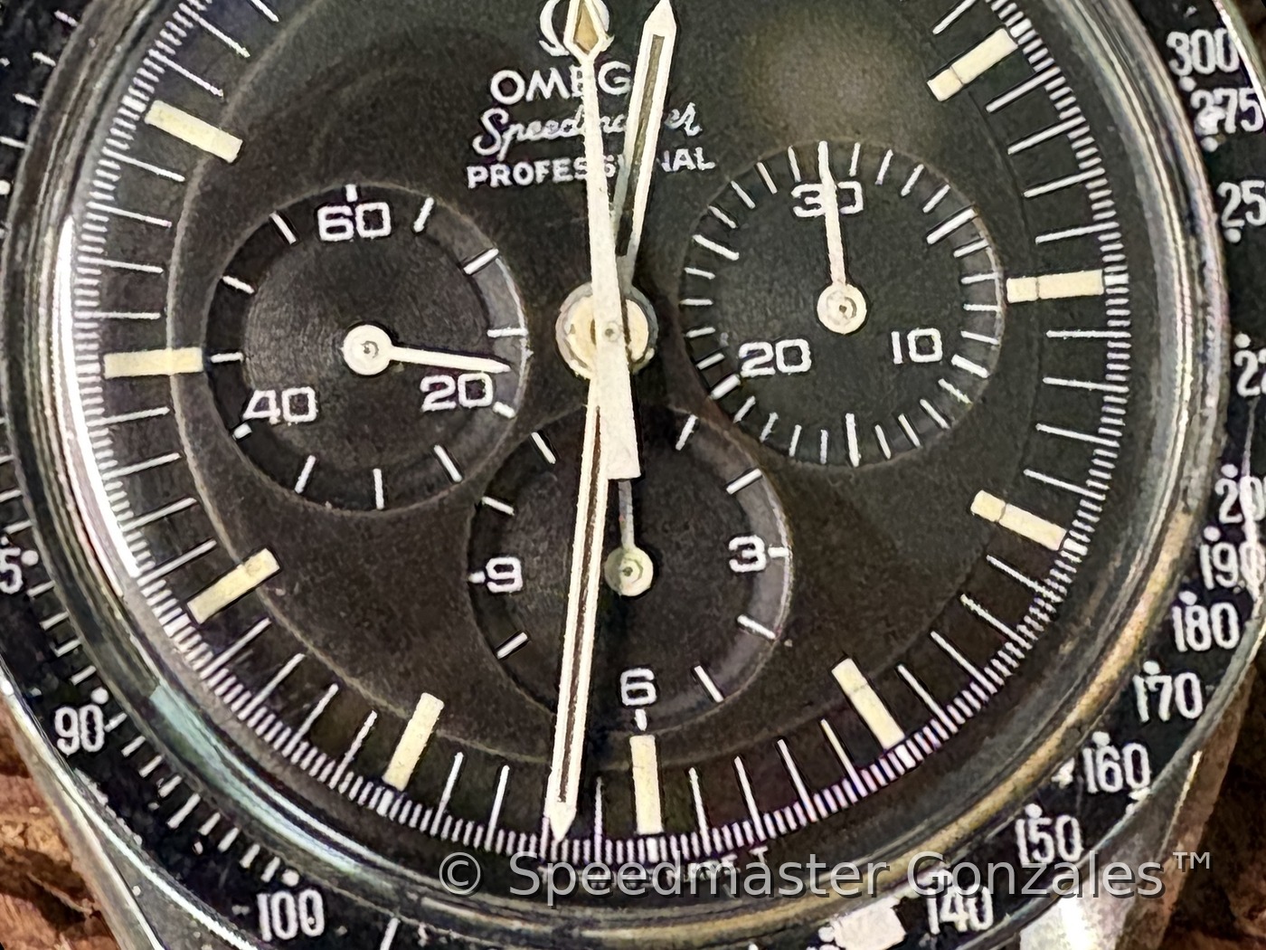 The collector's Speedmaster on a worn leather strap, resting on carved wood