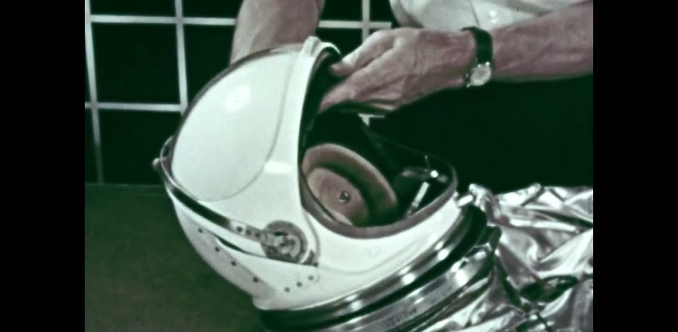 An astronaut's gloved hands adjusting a Mercury pressure helmet